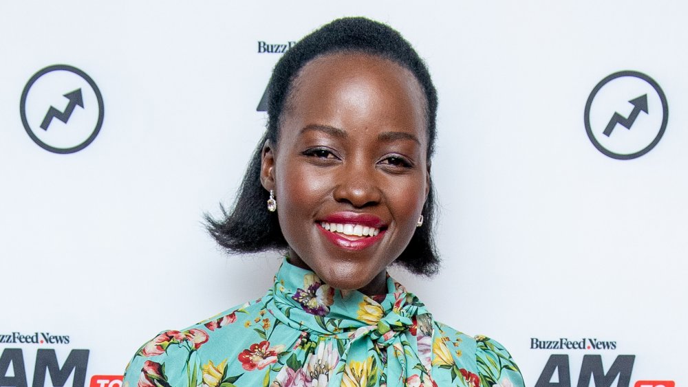 Lupita Nyong'o sonriendo con un vestido floral