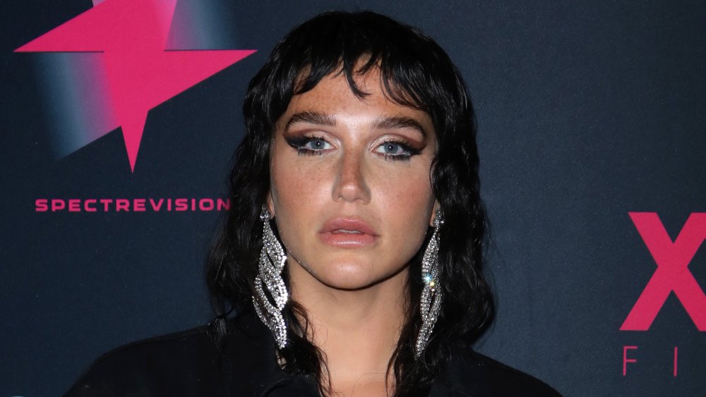 Kesha con cabello negro y grandes aretes de plata