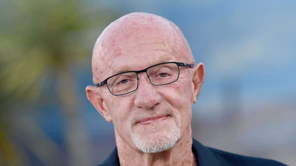 Jonathan Banks sonriendo, con gafas de montura negra puesta