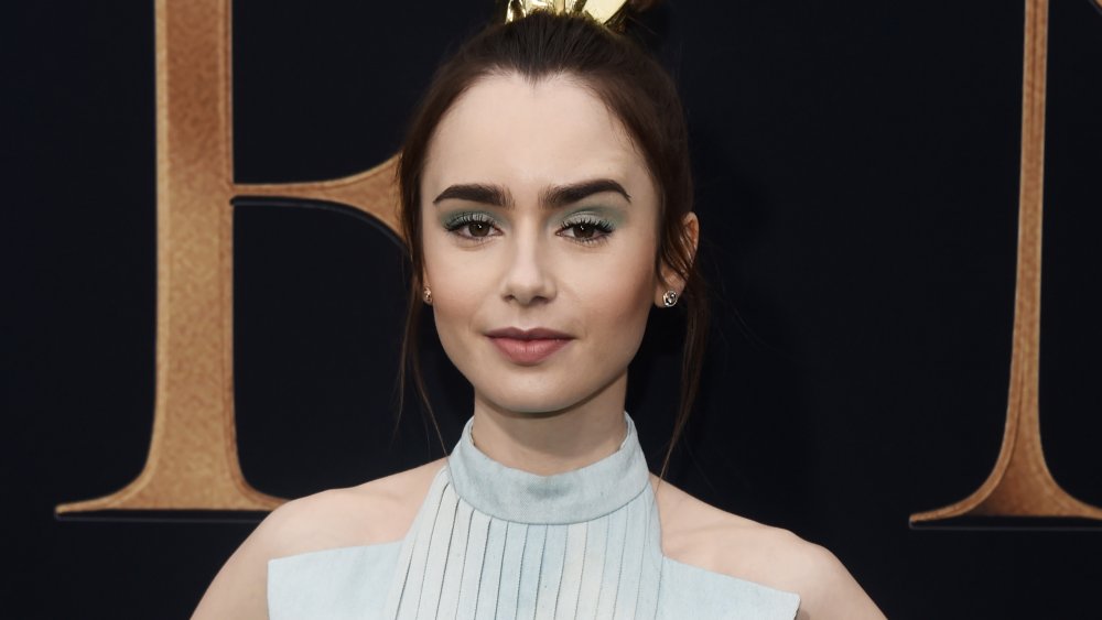 Lily Collins con una leve sonrisa y una ceja arqueada. 