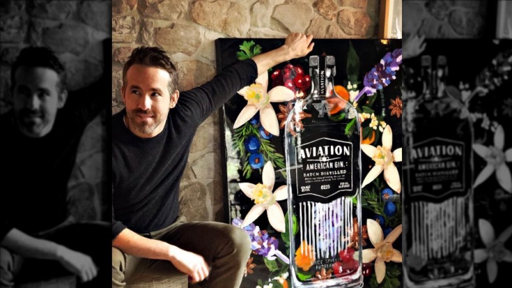 Ryan Reynolds posando con una pintura de una botella de ginebra Aviation