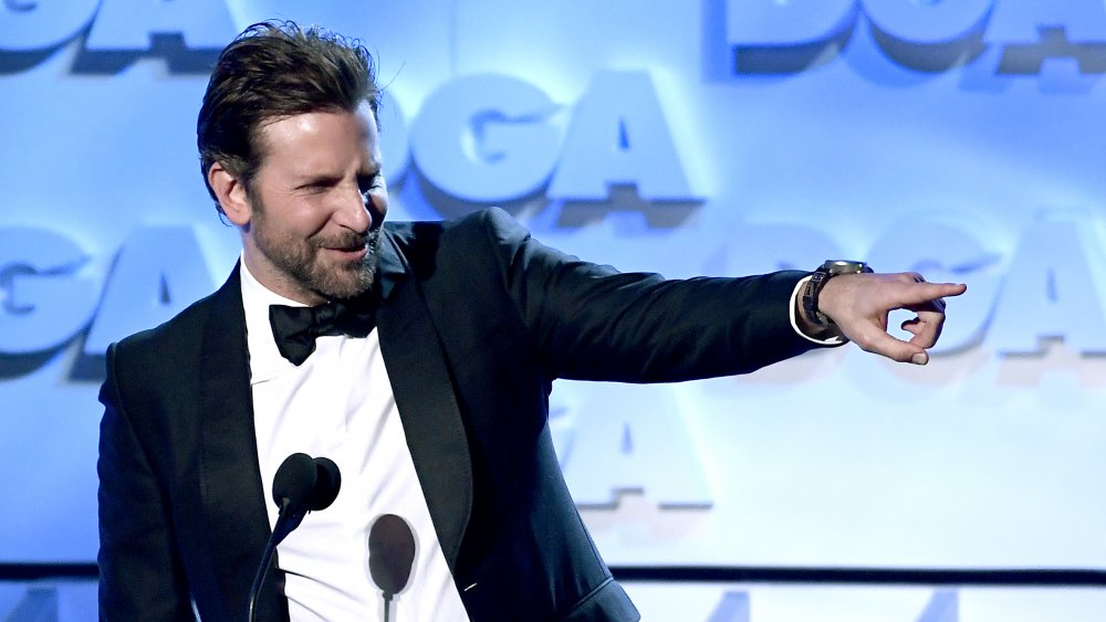 Bradley Cooper señalando fuera del escenario durante una aparición en un espectáculo de premios 