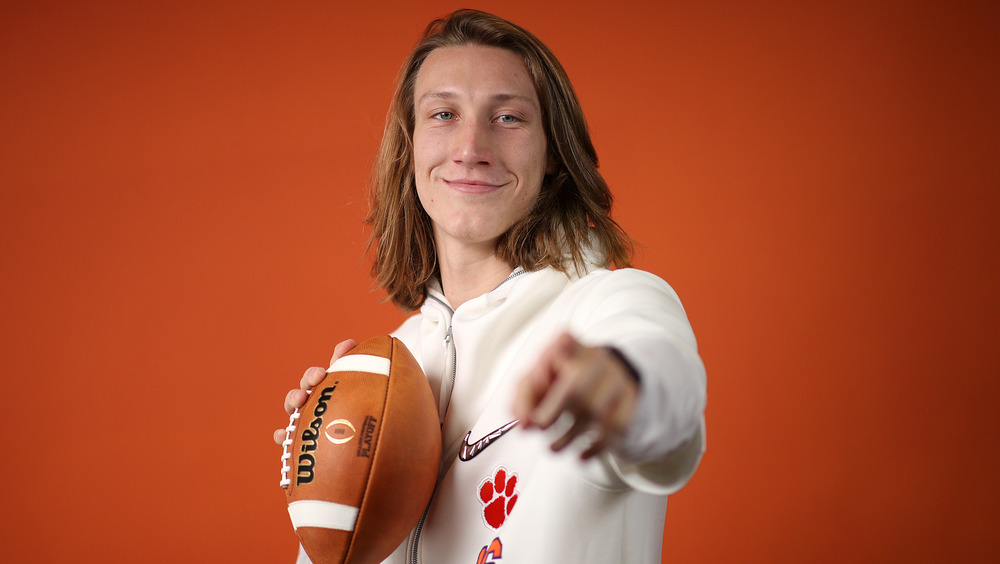 Trevor Lawrence sosteniendo una pelota de fútbol y apuntando a la cámara 