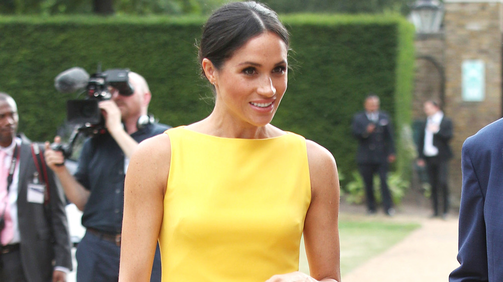 Meghan Markle caminando con un vestido amarillo