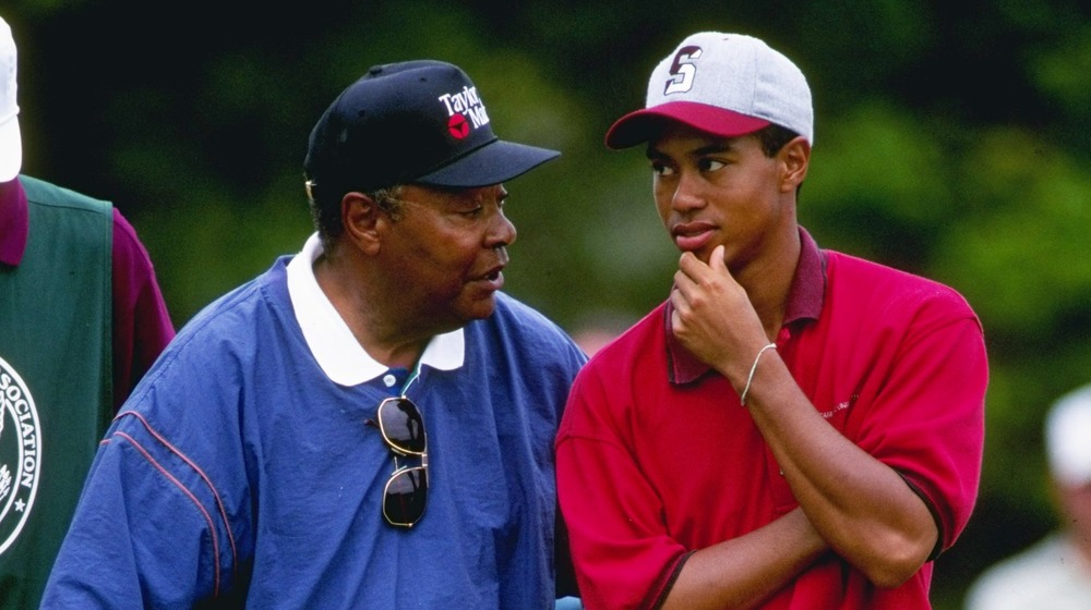 Earl Woods y Tiger Woods hablando en el campo de golf