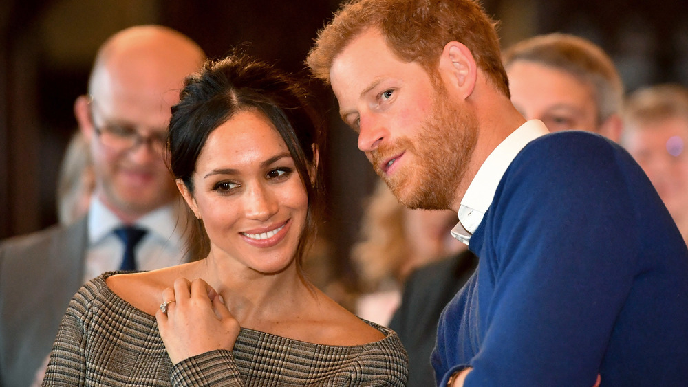 Meghan Markle se ríe con un top sin hombros mientras el príncipe Harry le susurra al oído