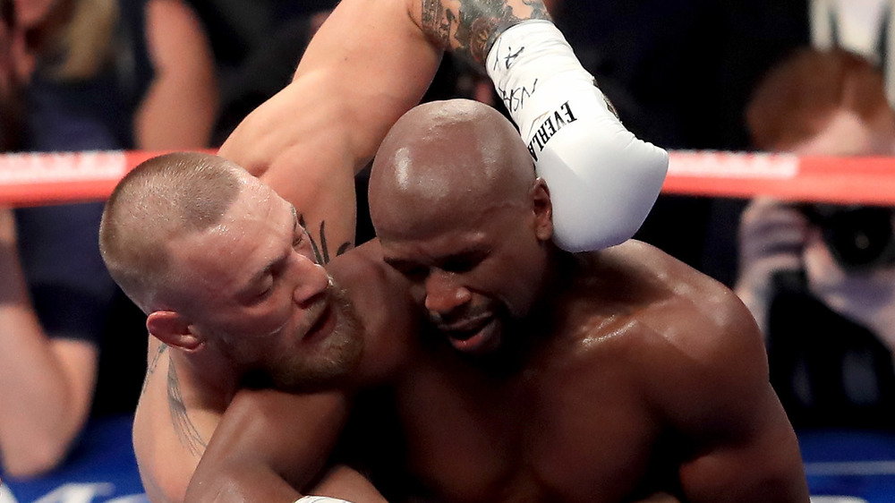 Conor McGregor y Floyd Mayweather en medio de un combate de boxeo