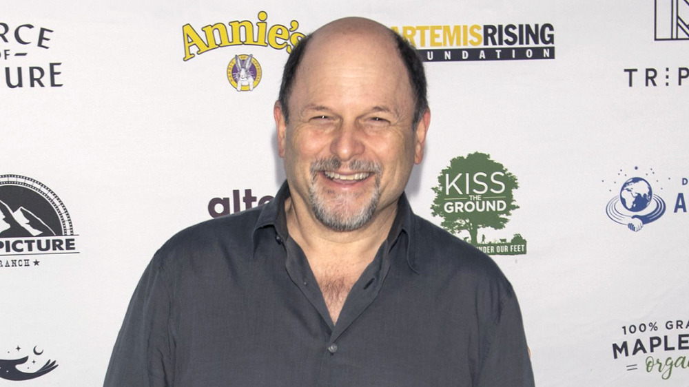 Jason Alexander sonriendo mientras posa para las cámaras