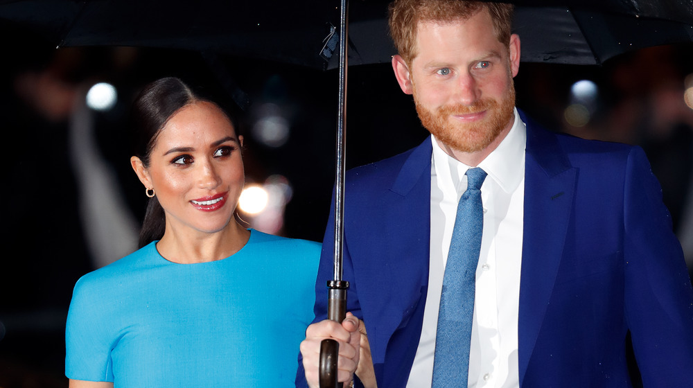 Meghan Markle y el príncipe Harry están bajo una sombrilla en un evento