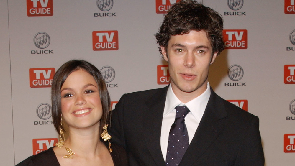 Rachel Bilson y Adam Brody sonriendo en un evento de alfombra roja 