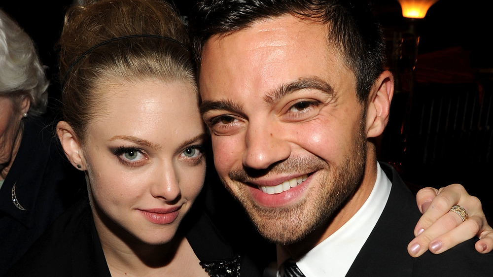 Amanda Seyfriend y Dominic Cooper sonriendo mejilla con mejilla