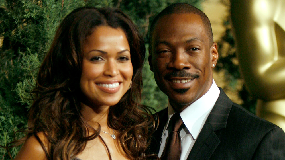 Tracey Edmonds y Eddie Murphy sonriendo en una alfombra roja