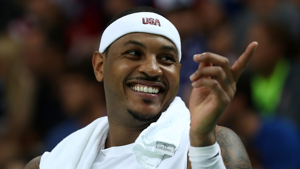 Carmelo Anthony sonriendo y apuntando fuera de cámara