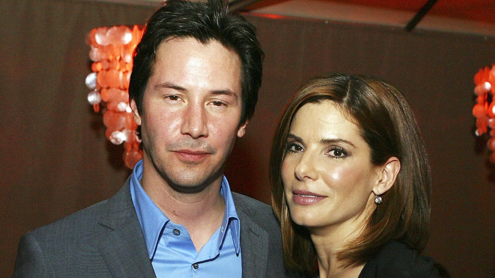 Keanu Reeves de pie junto a Sandra Bullock