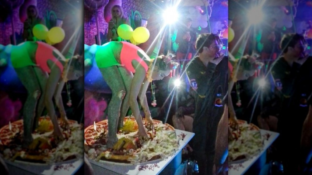 Miley Cyrus de pie sobre su pastel de pizza en su fiesta de cumpleaños número 22