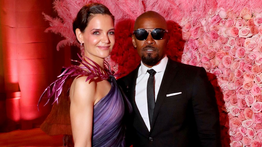 Katie Holmes y Jamie Foxx sonriendo en una alfombra roja 