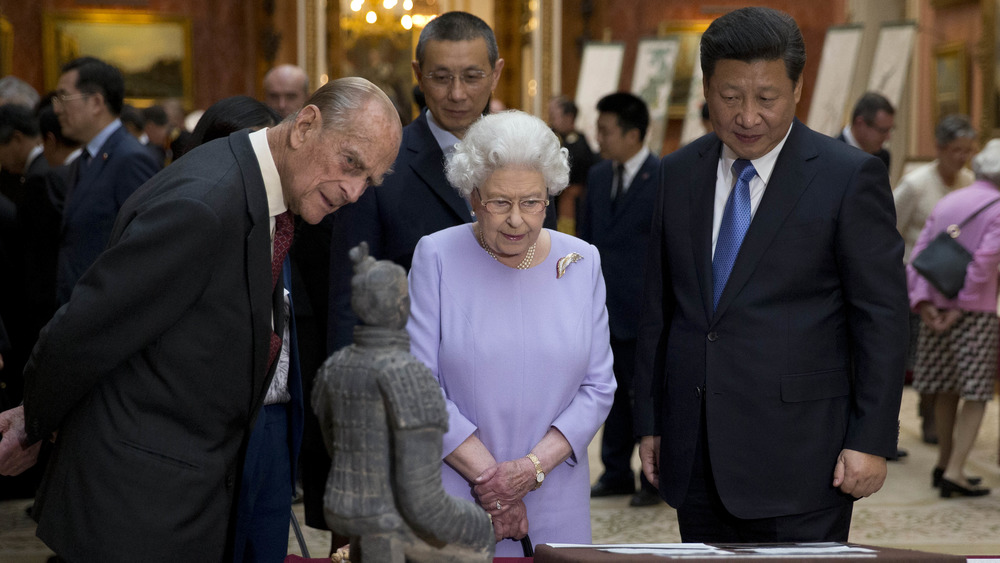 El príncipe Felipe, la reina Isabel y Xi Jinping mirando artefactos