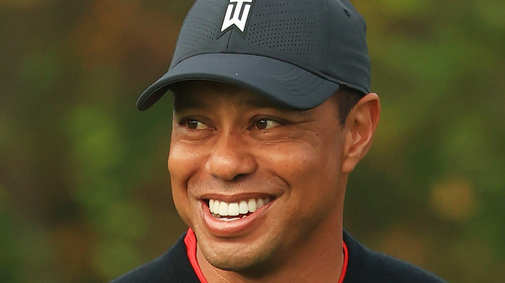 Tiger Woods, sonriendo, con gorra, jugando al golf 