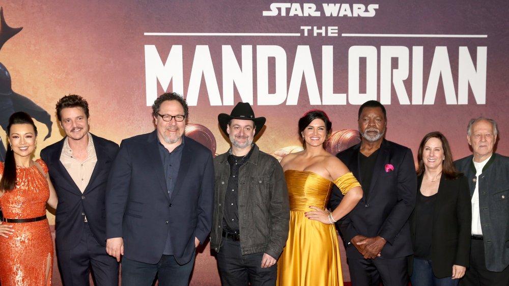 El elenco de Mandalorian frente al póster promocional