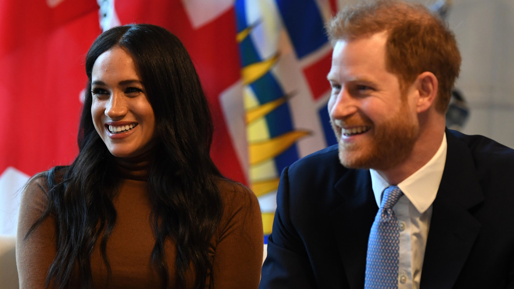 Meghan Markle y el príncipe Harry sonriendo mientras están sentados