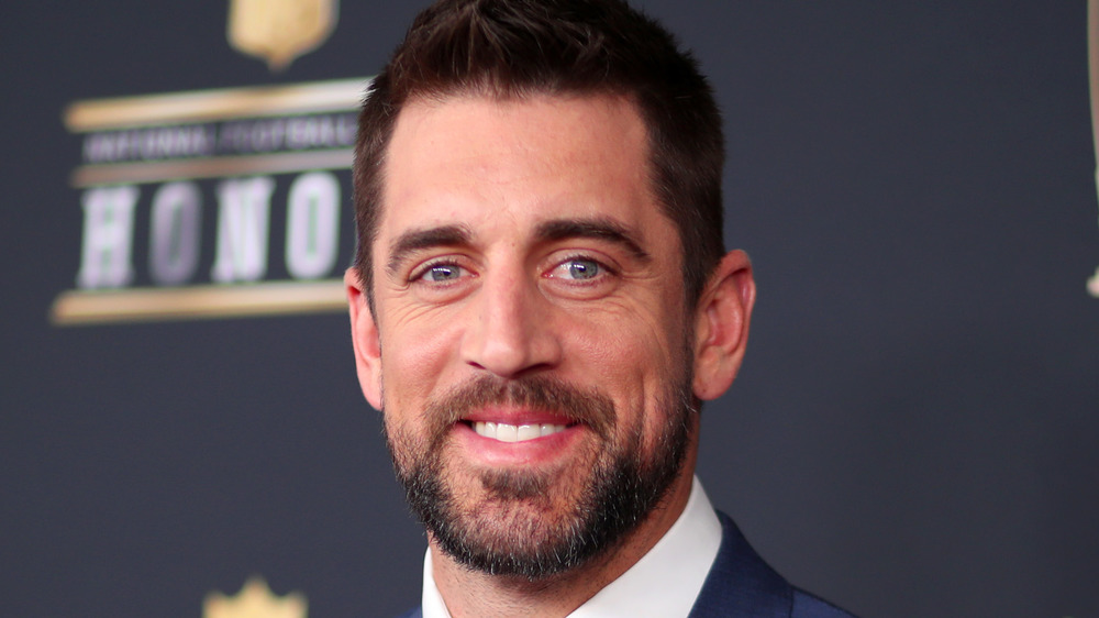 Aaron Rodgers sonríe con un traje.