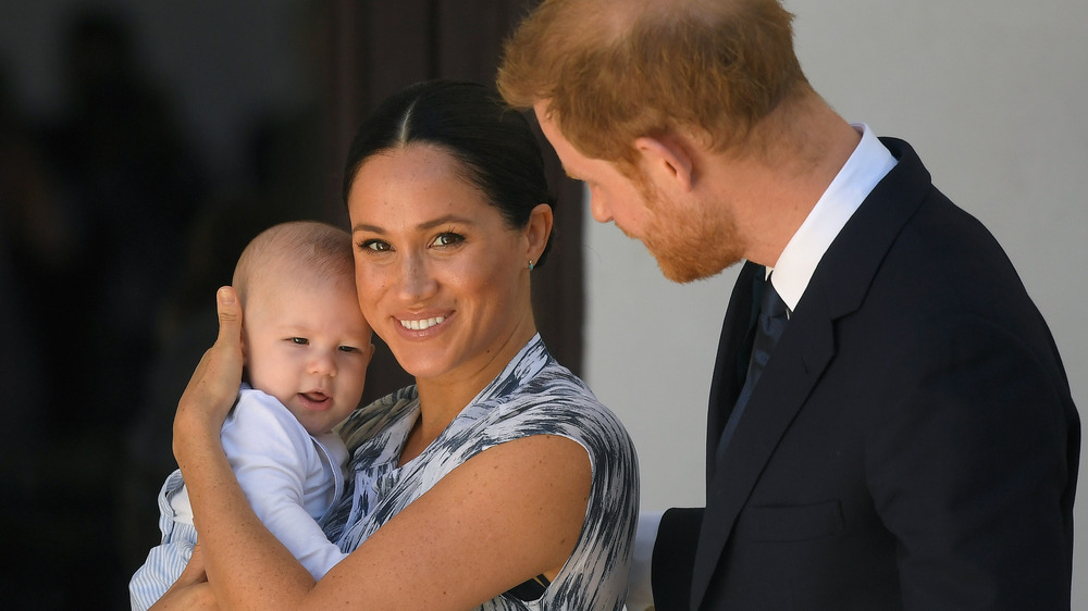 Meghan Markle sosteniendo a su hijo Archie mientras está de pie con el príncipe Harry