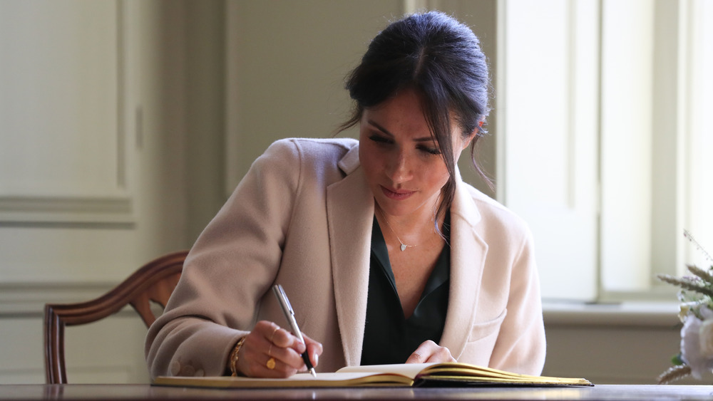 Meghan Markle escribiendo en un escritorio