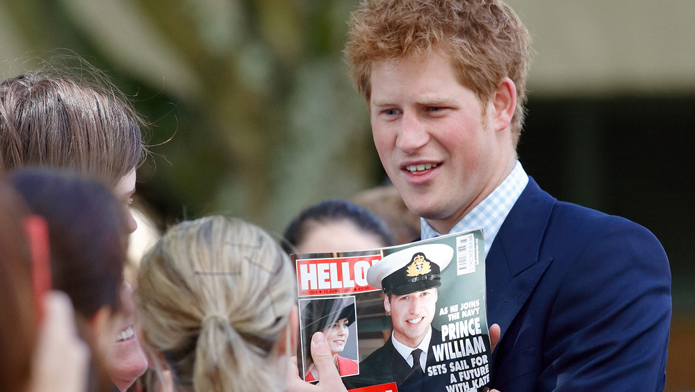 El príncipe Harry sostiene una foto del príncipe William en un tabloide