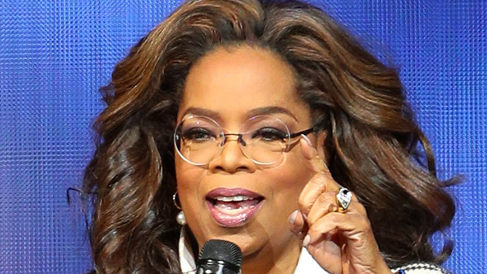 Oprah Winfrey hablando por un micrófono con gafas