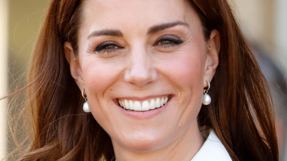 Kate Middleton sonriendo mientras usa aretes de perlas