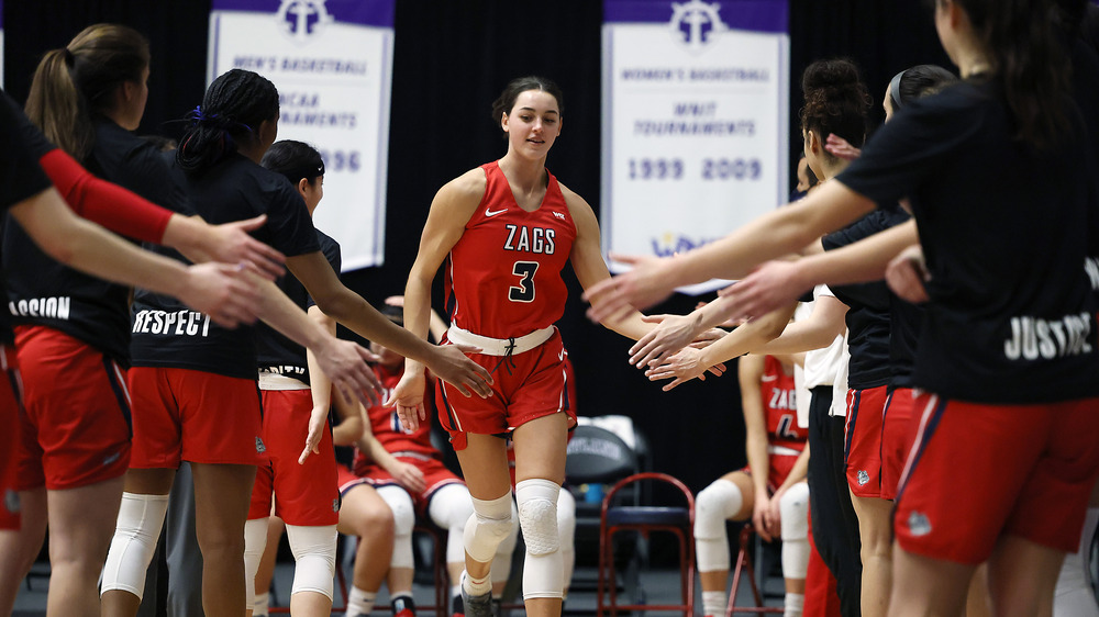 Jenn Wirth sonríe mientras choca los cinco con sus compañeros de equipo en la cancha