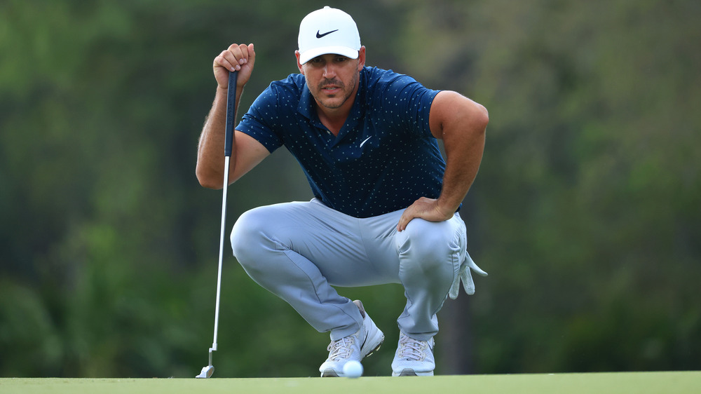 Brooks Koepka en cuclillas en un campo de golf