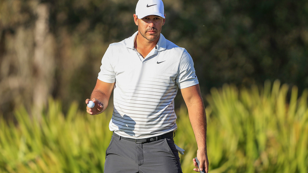 Brooks Koepka caminando con una pelota de golf en la mano