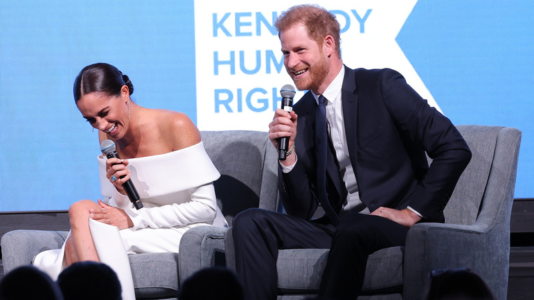 Meghan Markle y el príncipe Harry riéndose en el escenario