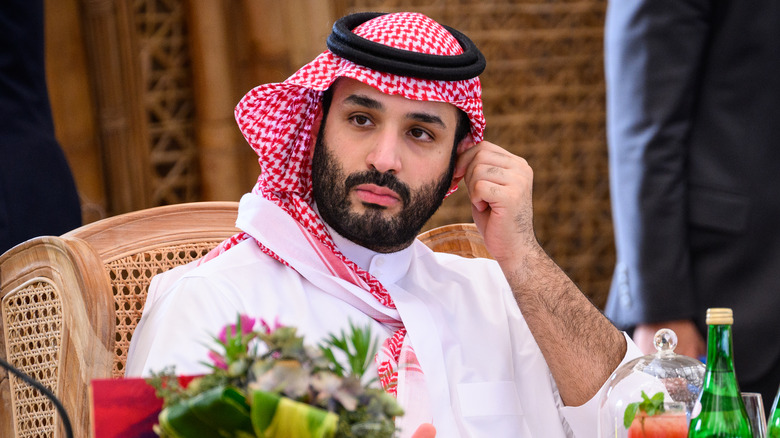 Mohammed Bin Salman mirando hacia un lado, con la mano en la oreja