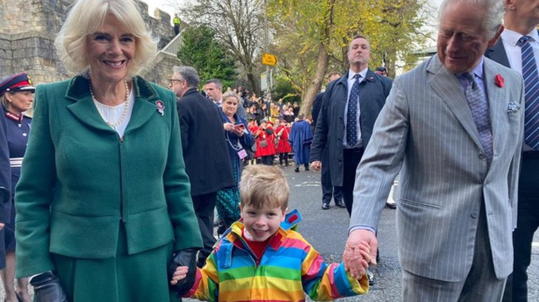 Camilla y Charles sosteniendo la mano del niño 