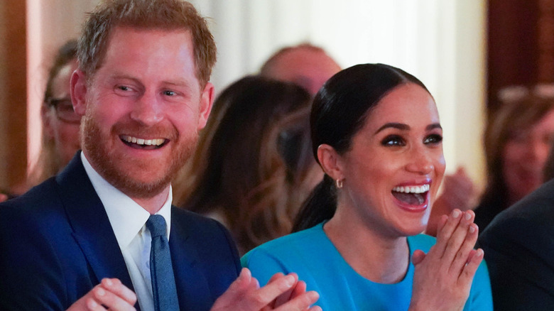 El príncipe Harry y Meghan Markle riendo y aplaudiendo