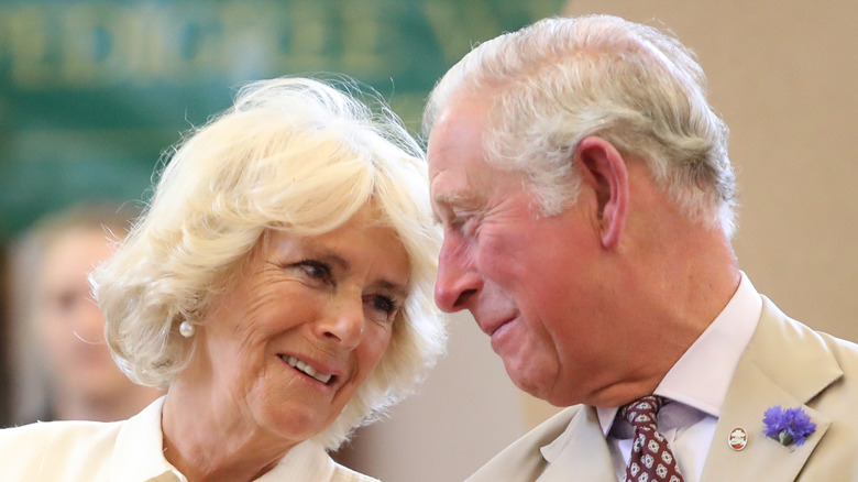 Camilla Parker Bowles y el rey Carlos mirándose.