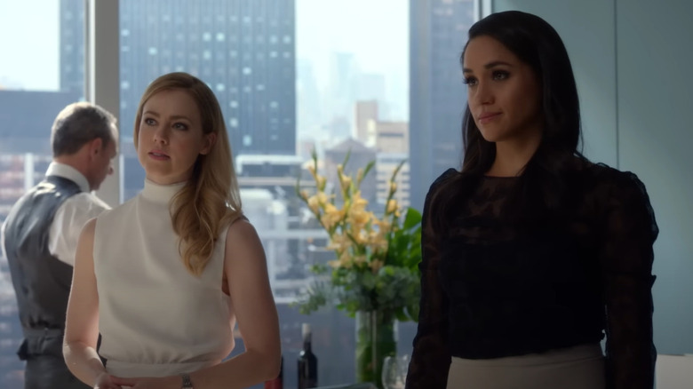 Amanda Schull y Meghan Markle con un rascacielos de fondo