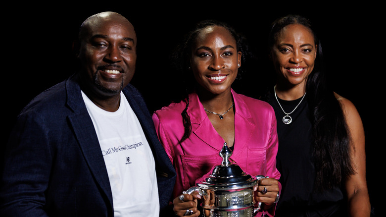 Corey, Coco y Candi Gauff posando junto a Coco sosteniendo su trofeo del US Open