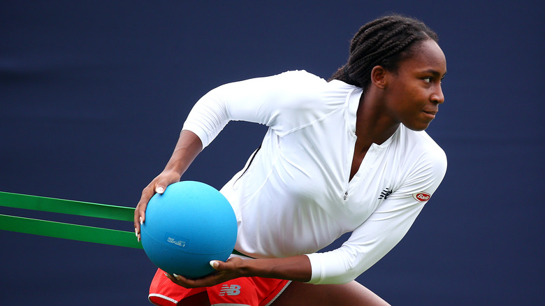 Coco Gauff haciendo ejercicio con una banda de resistencia y una pelota azul