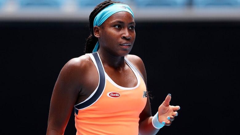 Coco Gauff con top naranja y diadema azul claro