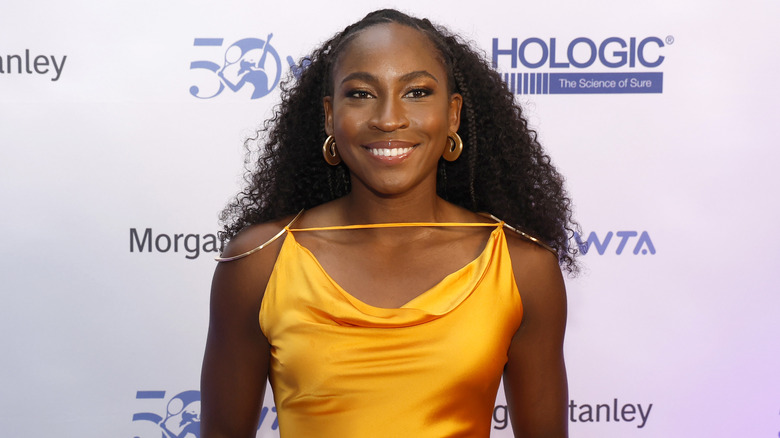 Coco Gauff sonriendo con un vestido mostaza