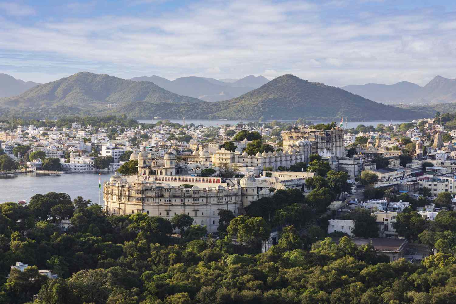 Vista elevada del Palacio de la ciudad, la ciudad antigua de Udaipur y el lago Pichola con las colinas Araveli al fondo