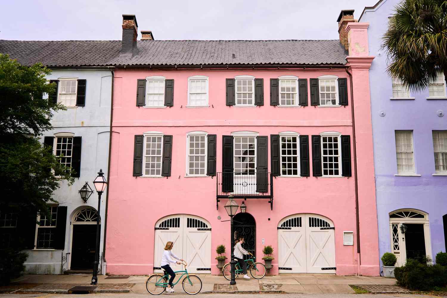 Dos personas andan en bicicleta por la calle de casas coloridas y luminosas en Charleston, SC