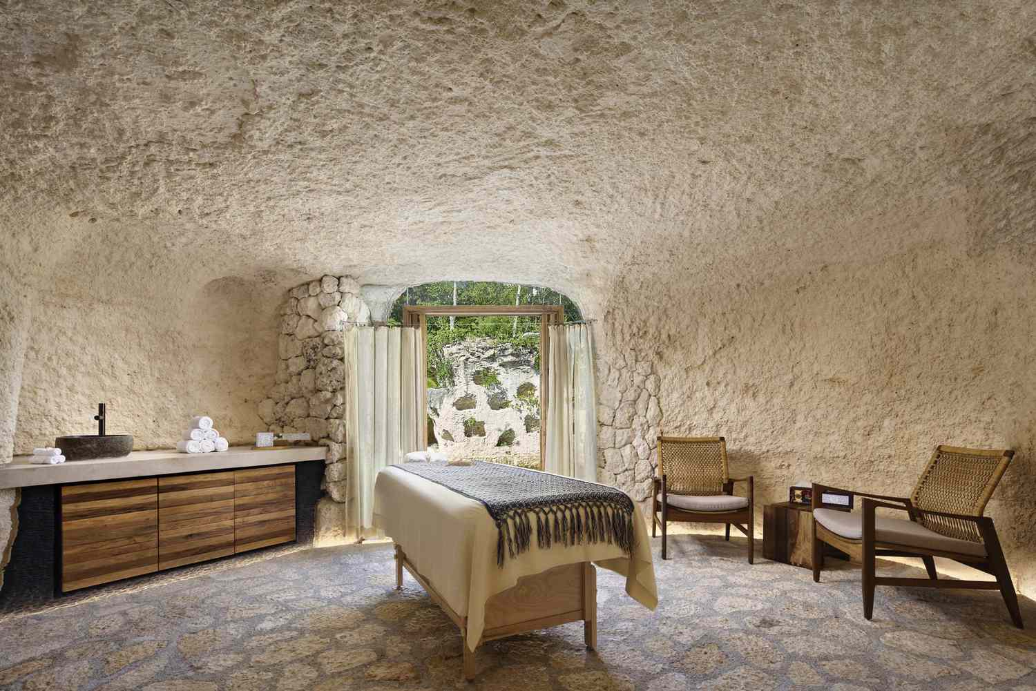 Sala de spa que parece una cueva, las paredes, el suelo y el techo son de piedra. 