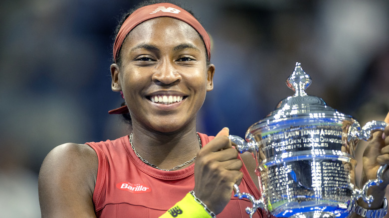 Coco Gauff sonriendo y sosteniendo su trofeo del US Open