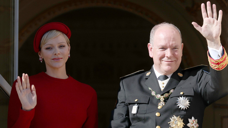 Sombrero rojo de la princesa Charlene, príncipe Alberto saludando