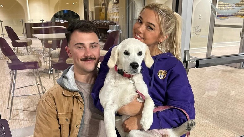 Paul Skenes y Olivia Dunne sentados con un perro