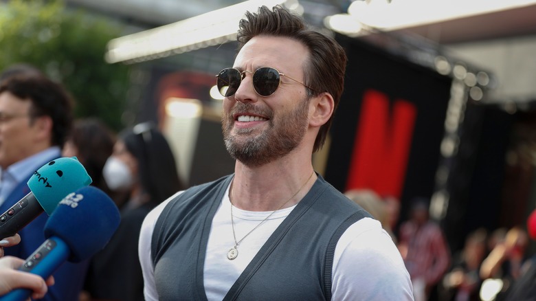 Chris Evans sonriendo frente a los micrófonos en la alfombra roja